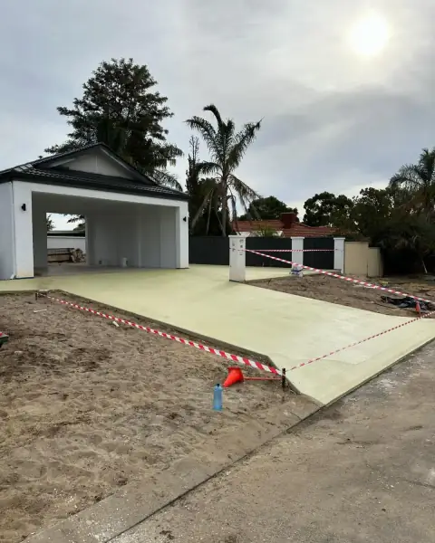 Freshly poured driveway slab in front of a garage, taped off and curing